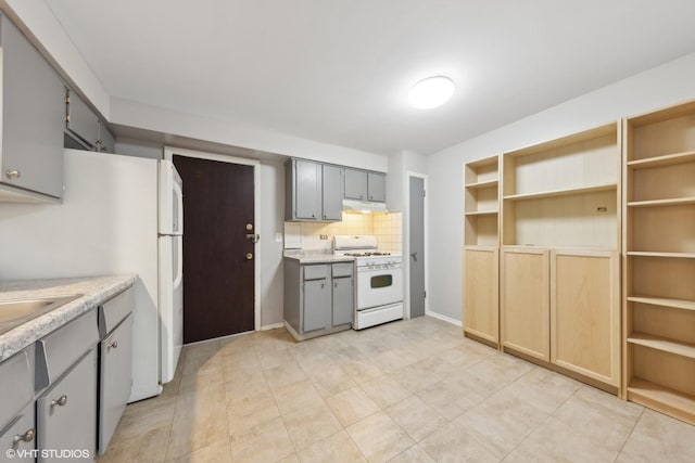 kitchen with gray cabinets, light tile patterned floors, backsplash, and white appliances