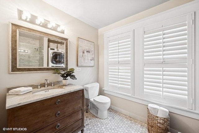 bathroom with plenty of natural light, toilet, vanity, and stacked washer and clothes dryer