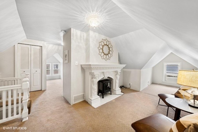 carpeted bedroom featuring a wood stove, a closet, a nursery area, and vaulted ceiling