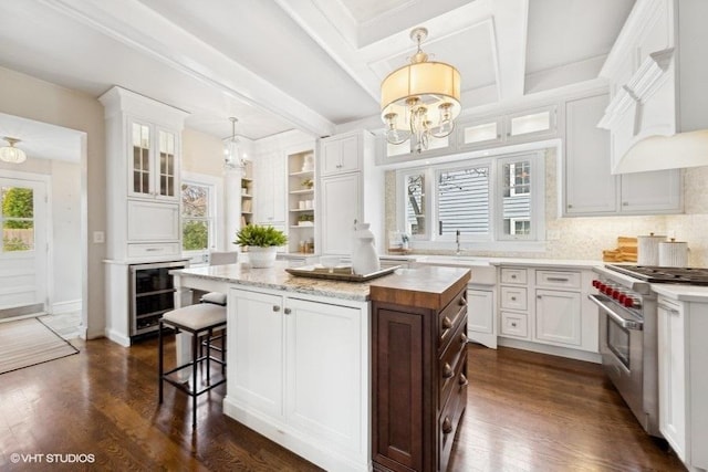 kitchen with a center island, high end range, a healthy amount of sunlight, and white cabinetry