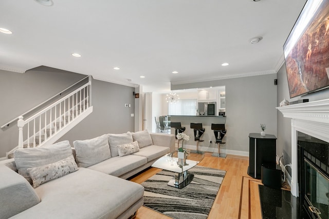 living room featuring crown molding, light hardwood / wood-style floors, and a notable chandelier