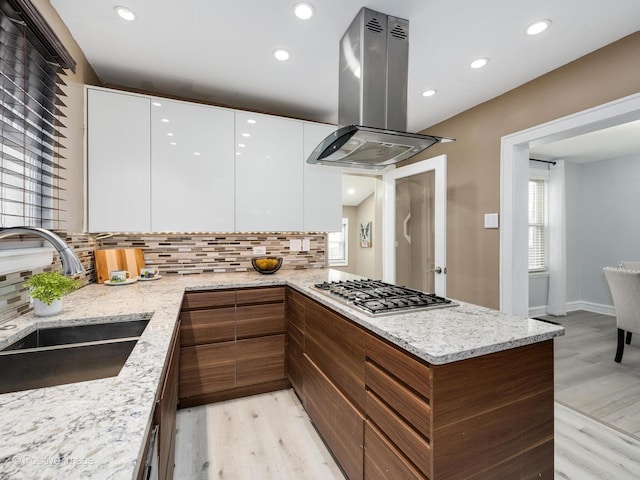 kitchen with island range hood, a sink, white cabinets, modern cabinets, and stainless steel gas stovetop