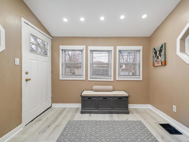 foyer with lofted ceiling, light wood-style floors, baseboards, and visible vents