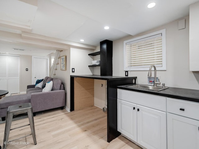 kitchen featuring open shelves, dark countertops, a sink, and white cabinetry