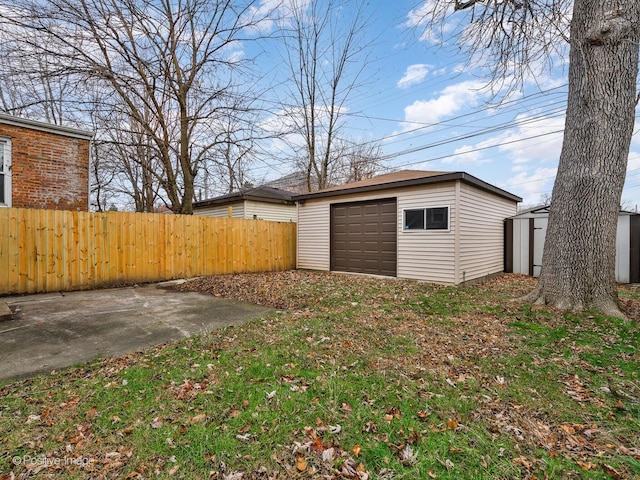 view of yard with a garage, an outbuilding, fence, and a patio