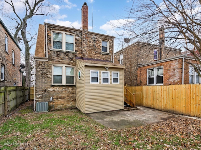 back of property featuring a patio, a fenced backyard, central air condition unit, brick siding, and a chimney