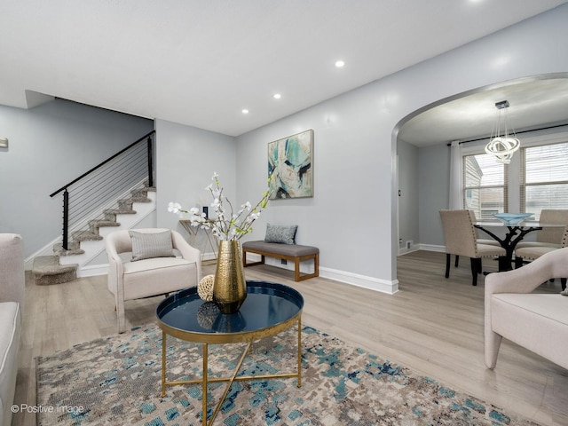 living room with light wood finished floors, baseboards, arched walkways, stairs, and recessed lighting