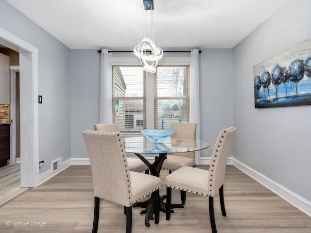 dining area with light wood-style floors, visible vents, a notable chandelier, and baseboards