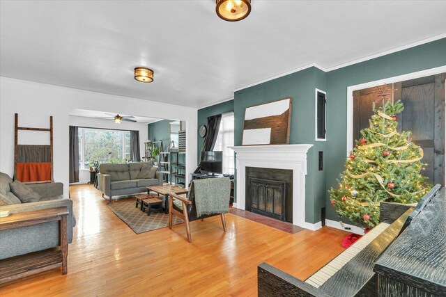 living room featuring wood-type flooring, ceiling fan, and crown molding