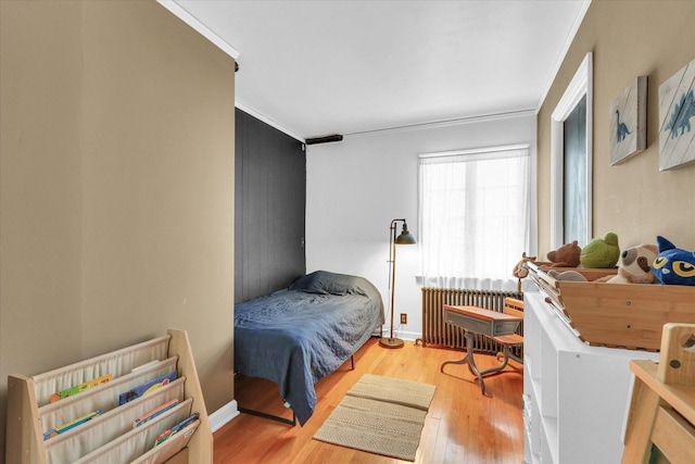 bedroom featuring light hardwood / wood-style floors, radiator, and ornamental molding