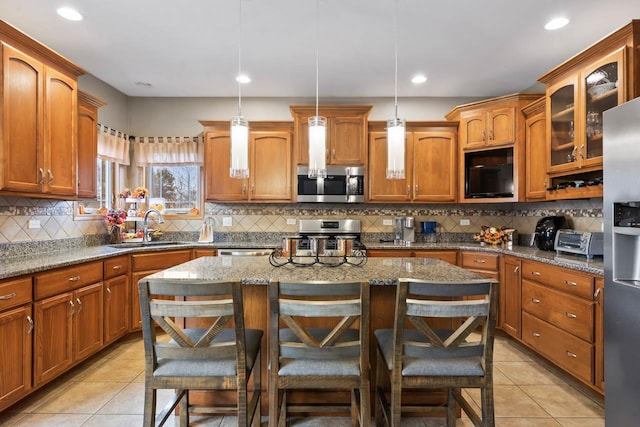 kitchen featuring sink, pendant lighting, a breakfast bar area, a kitchen island, and appliances with stainless steel finishes