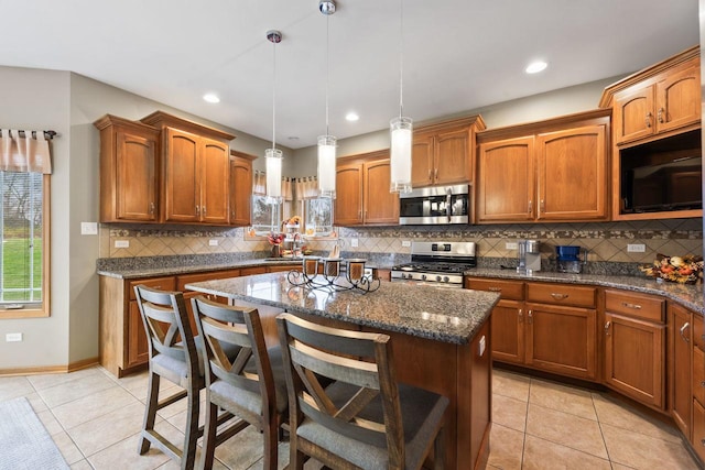 kitchen featuring pendant lighting, a kitchen island, appliances with stainless steel finishes, and dark stone counters