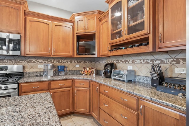 kitchen featuring decorative backsplash, appliances with stainless steel finishes, light tile patterned floors, and light stone countertops