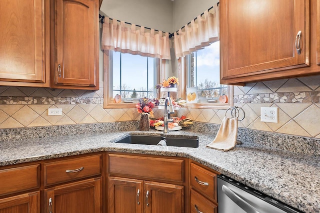 kitchen with stainless steel dishwasher, backsplash, light stone countertops, and sink