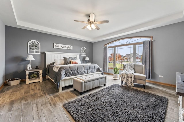 bedroom featuring wood-type flooring, a tray ceiling, and ceiling fan