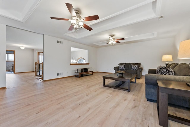 living room featuring a tray ceiling, ceiling fan, and light wood-type flooring