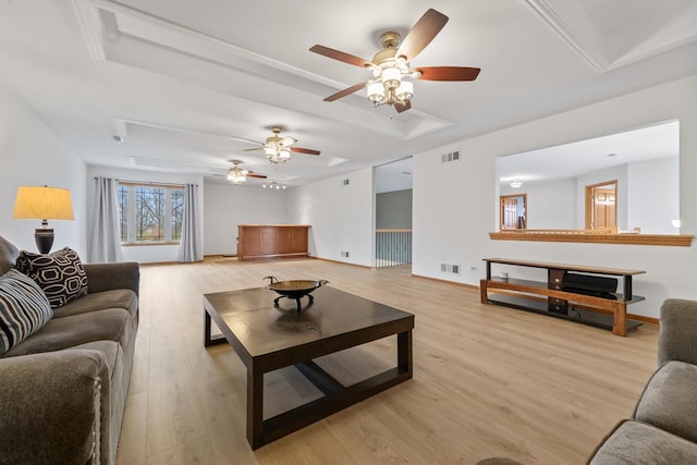 living room with a raised ceiling, ceiling fan, and light hardwood / wood-style flooring