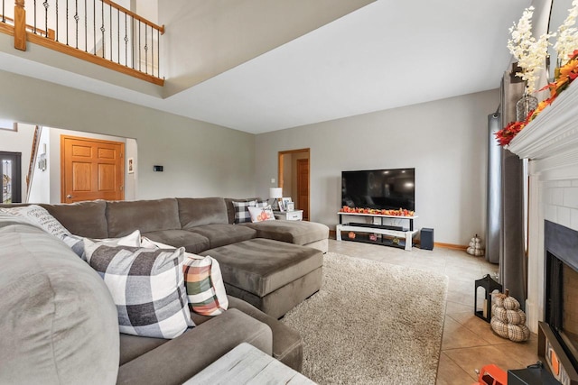 tiled living room featuring a tile fireplace and a towering ceiling