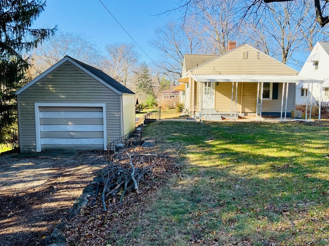 exterior space featuring covered porch, a garage, a yard, and an outbuilding