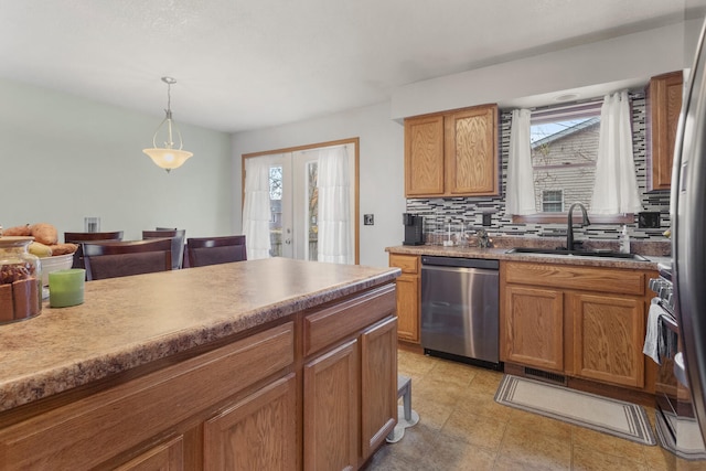 kitchen with sink, french doors, stainless steel appliances, tasteful backsplash, and decorative light fixtures