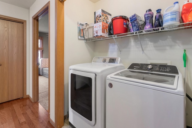 laundry room featuring washing machine and dryer and light hardwood / wood-style flooring