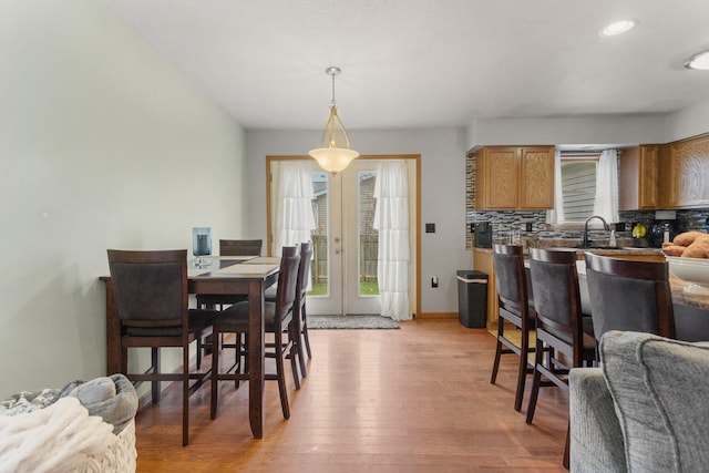 dining space with french doors, light hardwood / wood-style floors, and sink