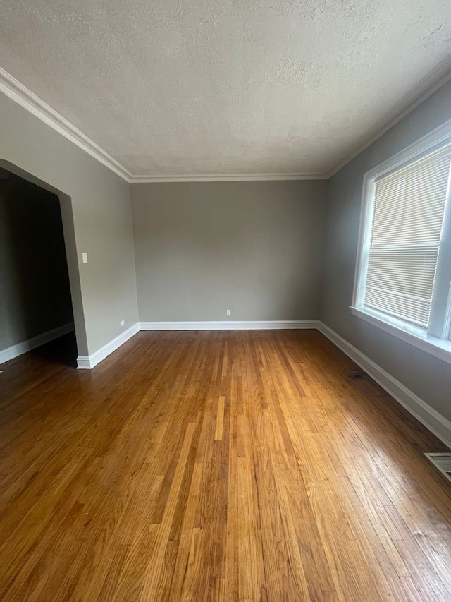 unfurnished room featuring crown molding, wood-type flooring, and a textured ceiling