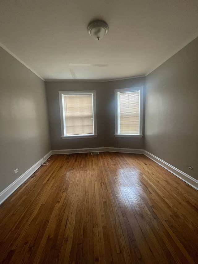 unfurnished room with plenty of natural light, ornamental molding, and hardwood / wood-style flooring