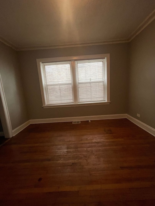 empty room with dark hardwood / wood-style flooring and ornamental molding