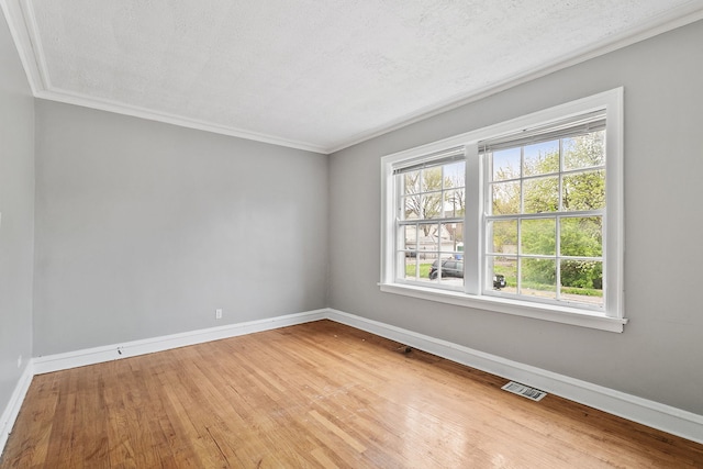 unfurnished room with crown molding, wood finished floors, visible vents, and baseboards