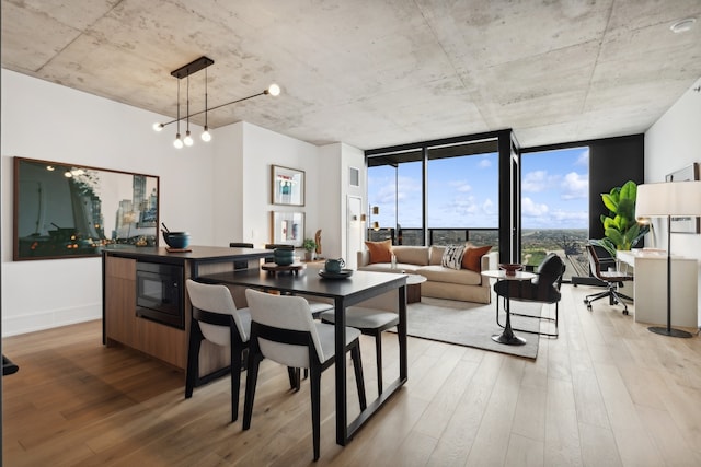 dining room featuring floor to ceiling windows, an inviting chandelier, and light wood-type flooring