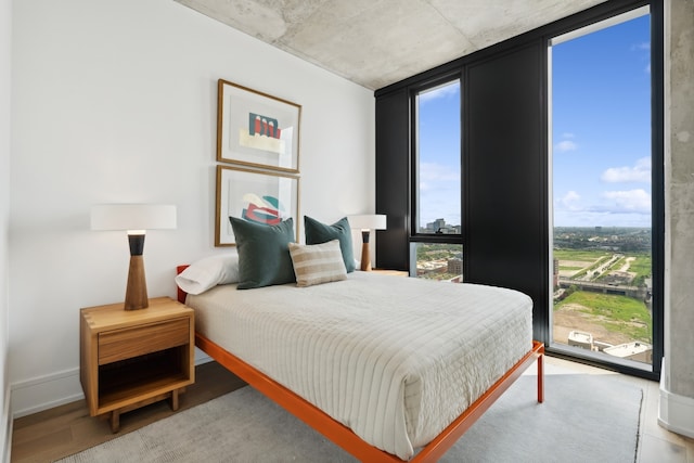 bedroom with expansive windows, light wood-type flooring, and multiple windows