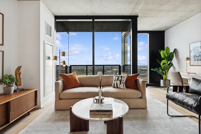 living room with a wealth of natural light, expansive windows, and light hardwood / wood-style floors