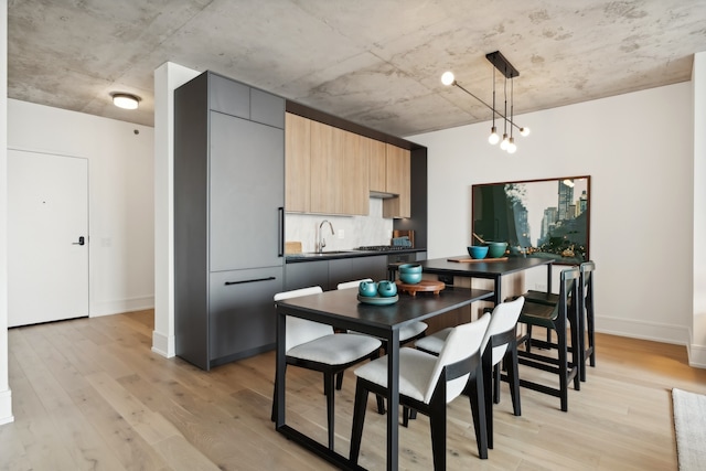 kitchen with light hardwood / wood-style flooring, hanging light fixtures, light brown cabinets, and sink