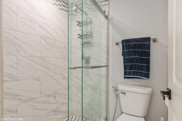 bathroom featuring a shower with door and toilet