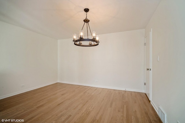 unfurnished room featuring wood-type flooring and an inviting chandelier