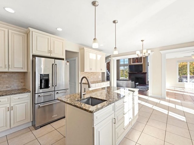 kitchen with a center island with sink, decorative light fixtures, high quality fridge, and tasteful backsplash