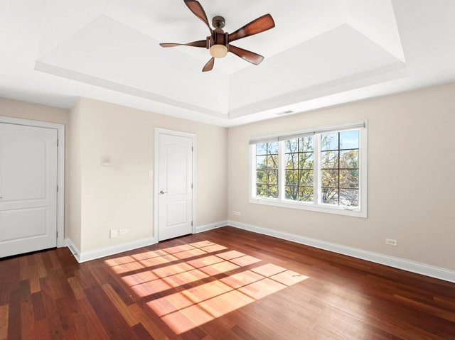 spare room featuring ceiling fan, dark wood-type flooring, and a tray ceiling