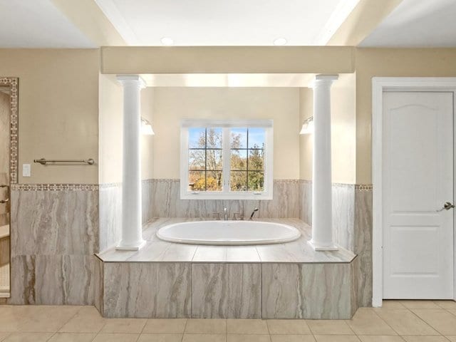 bathroom with tile patterned flooring and tiled bath