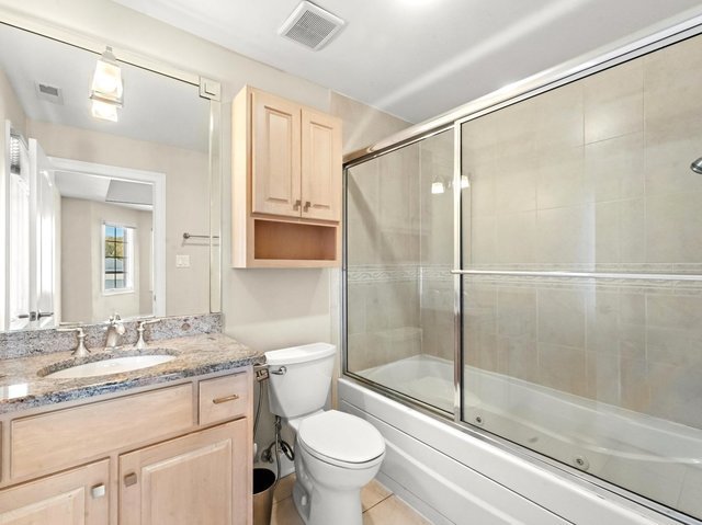 full bathroom featuring tile patterned flooring, vanity, toilet, and bath / shower combo with glass door