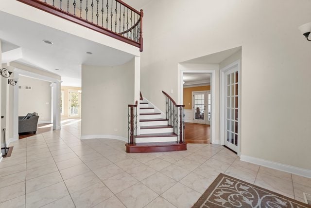 foyer entrance with plenty of natural light, decorative columns, a high ceiling, and french doors