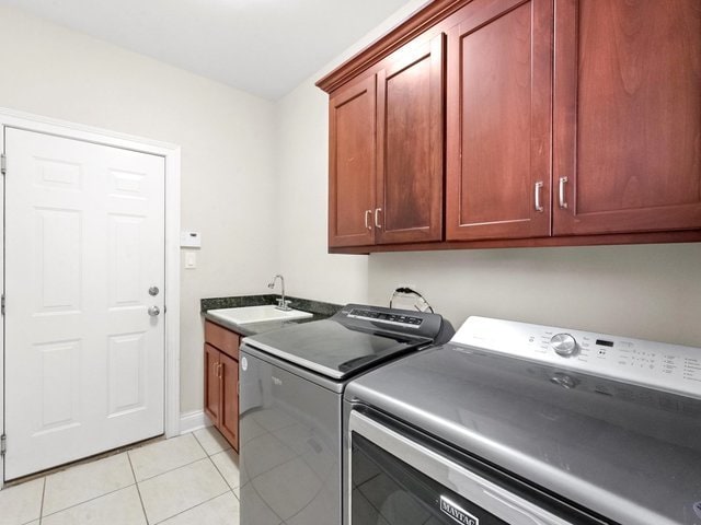 laundry area with cabinets, light tile patterned floors, sink, and washing machine and clothes dryer