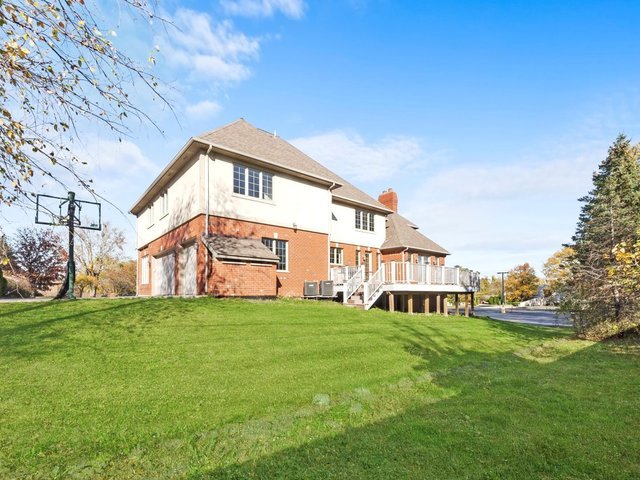 rear view of property with a yard, a garage, central AC unit, and a wooden deck