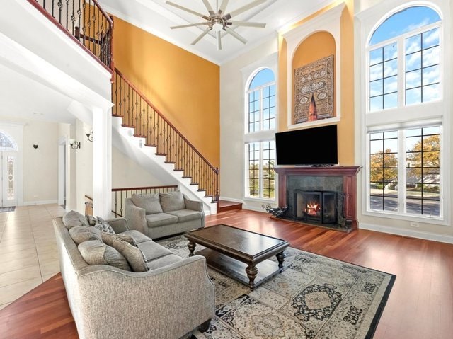 living room with crown molding, hardwood / wood-style floors, ceiling fan, and a high ceiling