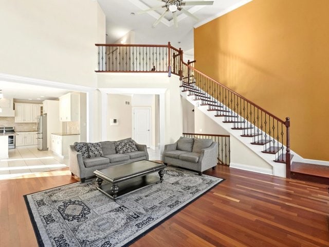 living room featuring a towering ceiling, hardwood / wood-style flooring, and ceiling fan