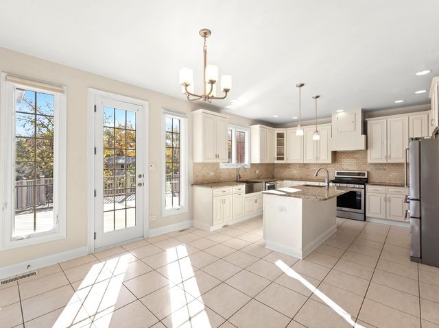 kitchen featuring sink, an island with sink, stainless steel appliances, and decorative light fixtures