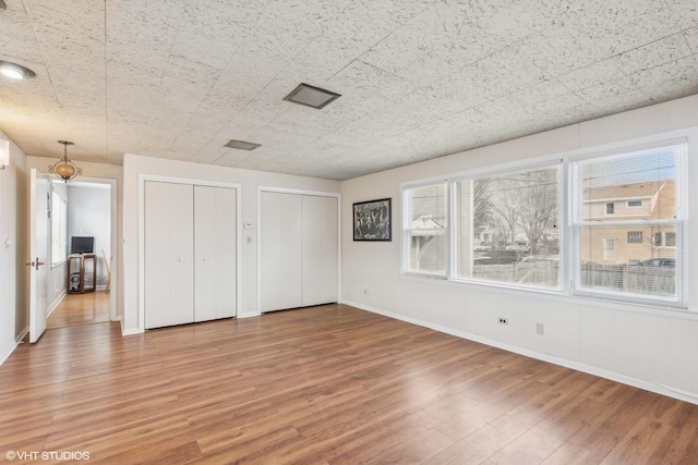 unfurnished bedroom featuring multiple closets and wood-type flooring