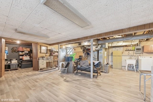 interior space with electric panel, light hardwood / wood-style flooring, washer / clothes dryer, and wood walls