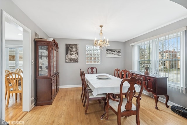 dining area with plenty of natural light, light hardwood / wood-style floors, and an inviting chandelier