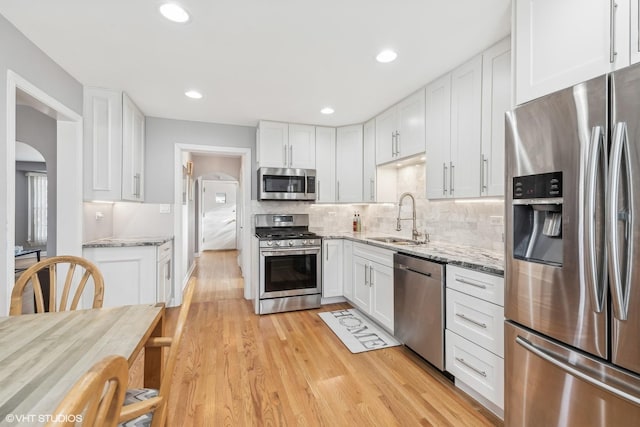 kitchen featuring white cabinets, light stone counters, sink, and appliances with stainless steel finishes